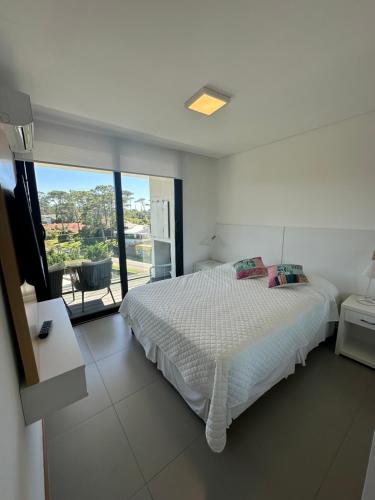- une chambre blanche avec un lit et un balcon dans l'établissement Sea Breezes, à Punta del Este