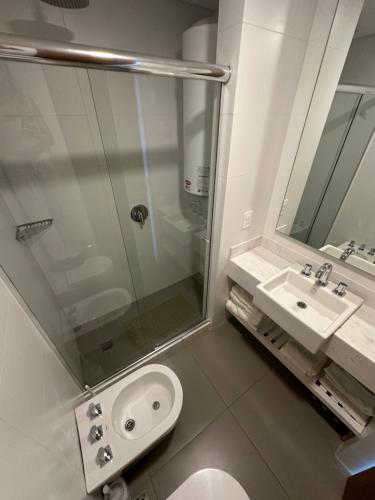 La salle de bains est pourvue d'une douche en verre et d'un lavabo. dans l'établissement Sea Breezes, à Punta del Este