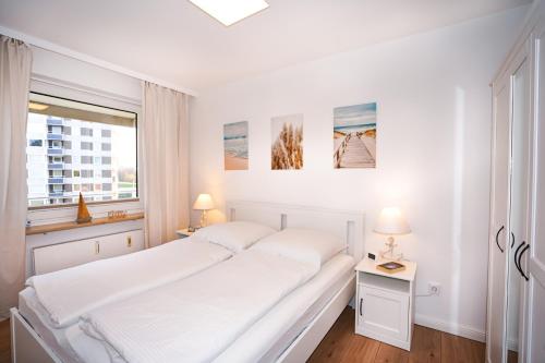 um quarto branco com 2 camas e uma janela em Hanseat I Whg 34 em Grömitz