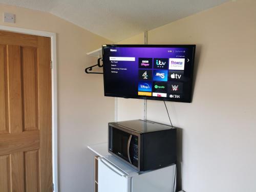 TV colgada en una pared con microondas en Impeccable 1-Bed Lodge in Eastleigh, en Eastleigh