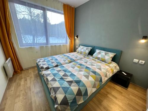 a bedroom with a bed with a large window at Pine Tree - charming apartment in Bansko