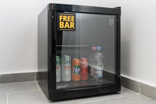 a small refrigerator with drinks and a free bar sign at Bada Bing Residence in Braşov