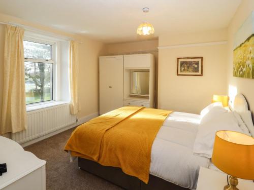 a bedroom with a bed with a yellow blanket on it at The Stables in Wigton