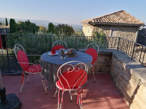 una mesa con sillas rojas en un patio con vistas en Maison d'hôtes, en Crillon-le-Brave