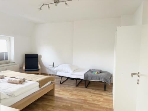 a bedroom with two beds and a chair at Möbliert-nahe STARLIGHT EXPRESS in Bochum -WLAN-Netflix-Loggia oder Terrasse in Bochum