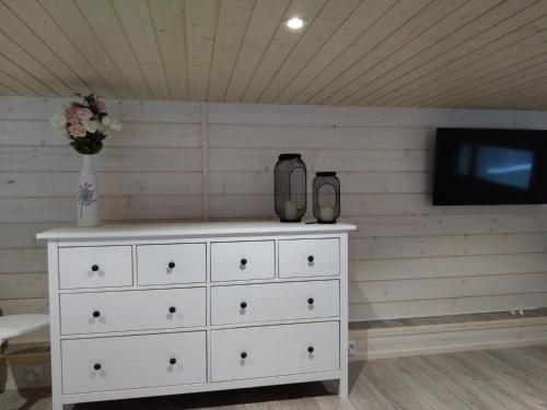 a white dresser with a tv on a wall at Koivuniemen Tila 3 in Säkylä