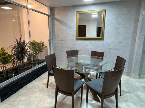 uma sala de jantar com uma mesa de vidro e cadeiras em Departamento Los viñedos em Ica