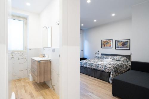 a white bedroom with a bed and a couch at La dolce vita rooms in Rome