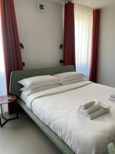 a bedroom with a large white bed with red curtains at OMÍ Aparthotel in Caserta