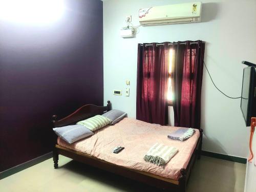 1 dormitorio con 1 cama con cortinas moradas y TV en casa bon souvenirs, en Pondicherry
