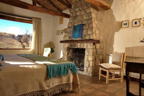 1 dormitorio con 1 cama y chimenea de piedra en Estancia Las Carreras en El Mollar