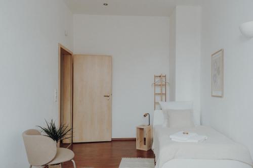 a white bedroom with a bed and a wooden door at NEU! Weinstraßenzauber Altbauwohnung mitten in NW in Neustadt an der Weinstraße