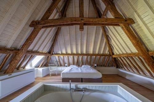 Cette grande chambre mansardée comprend un lit et une baignoire. dans l'établissement Domaine du Château de Haltinne-Maison du Jardinier, à Gesves