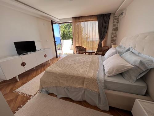 een slaapkamer met een groot bed en een televisie bij Vila Bella Vista in Herceg-Novi
