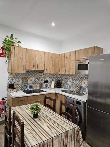 a kitchen with a table and a stainless steel refrigerator at Nalkia in Villanueva de la Concepción