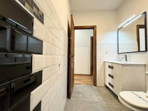 y baño con aseo, lavabo y espejo. en Chueca Stylish Flat 2BD in the City Center+Balcony, en Madrid