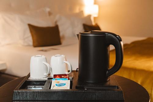 a table with a black coffee pot and cups on a bed at Cidnay Santo Tirso - Charming Hotel & Executive Center in Santo Tirso