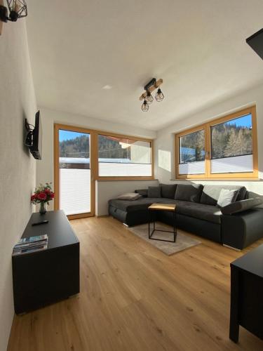 a living room with a black couch and a table at Ferienwohnungen Moser in Steinberg am Rofan