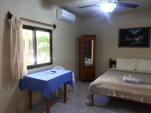 a bedroom with a bed and a table and a window at Beach Side Condos Caye Caulker by CCVH in Caye Caulker