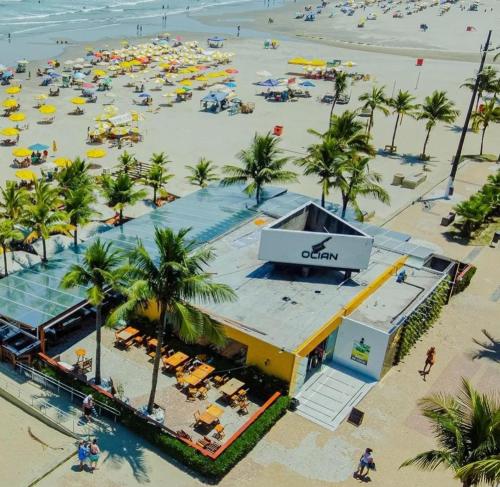 eine Aussicht über einen Strand mit Palmen und einem Gebäude in der Unterkunft Apartamento a 50 metros da Praia para utilização da piscina precisa de Atestado Médico in Praia Grande