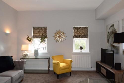 a living room with a yellow chair and a tv at The Stratford Suite Dunara 6 in Leamington Spa
