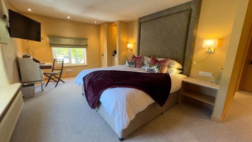 a bedroom with a large bed and a television at The Bittescombe Inn in Upton