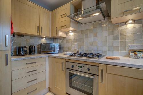 a kitchen with wooden cabinets and a stove top oven at The Vanbrugh Suites in Oxford