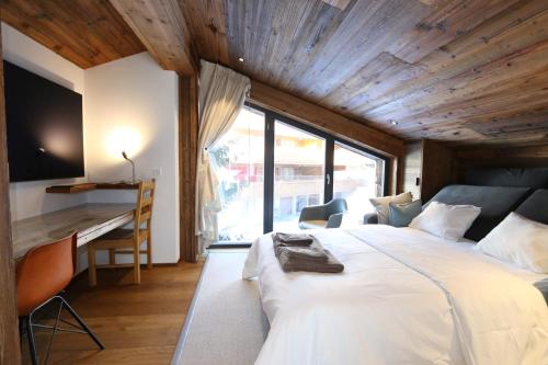 a bedroom with a large white bed and a desk at Heinrida in Saas-Fee
