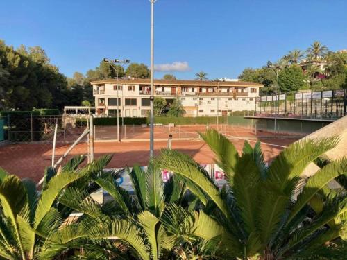 una pista de tenis frente a un edificio en Apartamento Buganvilla Pool en Muntanya la Sella