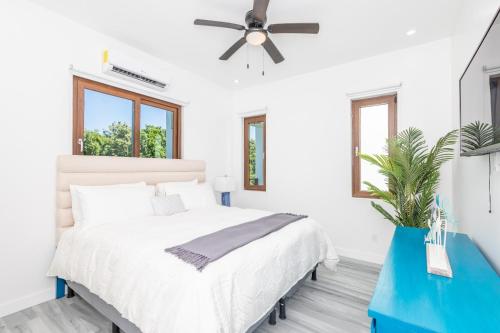 - une chambre blanche avec un lit et un ventilateur de plafond dans l'établissement Acqua di Mare Resort, à West Bay