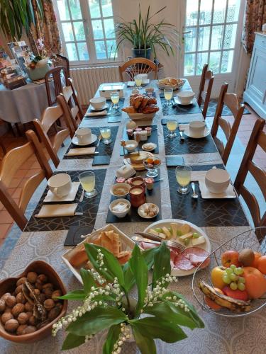 Una mesa larga con platos de comida encima. en Chambres d'Hôtes de l'Ile du Saule, en Saumur