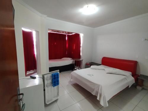 a bedroom with a bed and two windows with red curtains at Hotel Oliveira in Goiânia