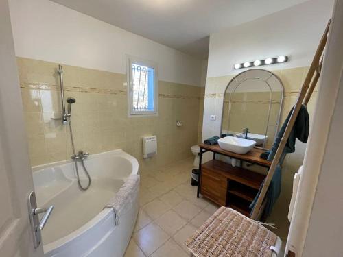 ein Badezimmer mit einer Badewanne, einem Waschbecken und einem Spiegel in der Unterkunft La maison d'Amélie, Villa climatisée piscine privée 4 Chambres, 3 sdb in Mazan
