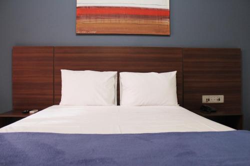 uma cama com lençóis brancos e uma cabeceira de madeira em Days inn by Wyndham Uberlândia em Uberlândia