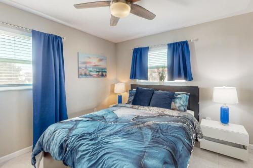 a bedroom with a bed with blue curtains and a ceiling fan at Dreaming on the Canal in Port Charlotte