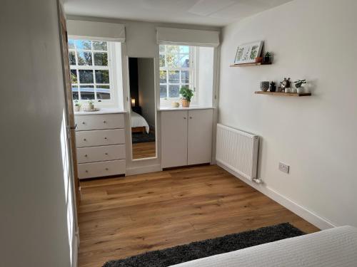 a bedroom with white walls and wooden floors and a hallway at Tiny House in Cosy Village in Milnathort