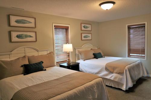 a bedroom with two beds and a lamp and windows at Bay Colony 761 - Lower in Nisswa