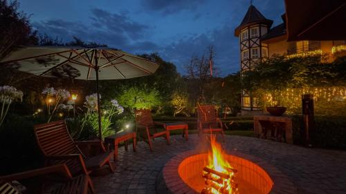 a fire pit in a patio with chairs and an umbrella at Carballo Hotel & Spa in Campos do Jordão