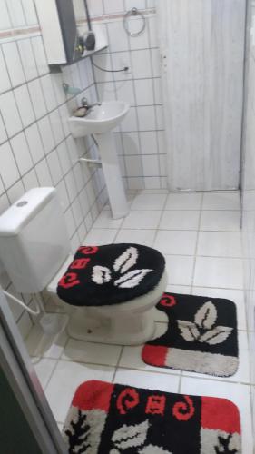 a bathroom with a toilet and a sink and two rugs at Beleza de Angra Apartamento Aconchegante in Angra dos Reis