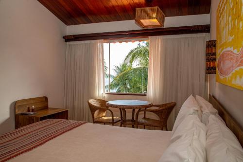 a bedroom with a bed and a table and a window at Serrambi Resort in Porto De Galinhas