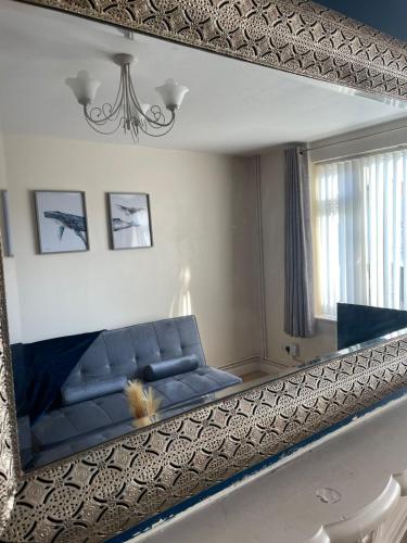 Spacious 4-bed House in Leicester في ليستر: مرآة تعكس أريكة زرقاء في غرفة المعيشة