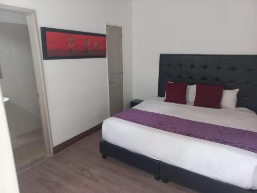 una camera da letto con un grande letto con cuscini rossi di Casa Hotel Mónaco a Bogotá