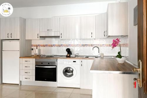 a kitchen with white cabinets and a washing machine at Las Playitas Sport&Golf in Las Playas
