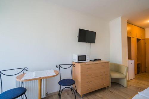 a room with a tv and a desk and chairs at Jade Panzio in Balatonföldvár