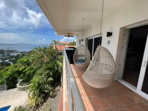 een balkon met 2 hangende rotan hangmatten bij Mandavilla Rose - Inspired USVI - Generator - Starlink in Cruz Bay