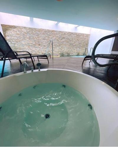 a bath tub filled with green water next to chairs at Departamentos en Uruguay al río, Dos Orillas, Colonia in Colonia del Sacramento