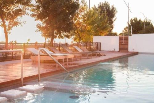- une piscine avec un bouquet de chaises longues à côté dans l'établissement Departamentos en Uruguay al río, Dos Orillas, Dazzler, Colonia, à Colonia del Sacramento