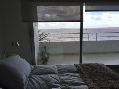 a bedroom with a bed and a view of the ocean at Departamentos en Uruguay al río, Dos Orillas, Dazzler, Colonia in Colonia del Sacramento