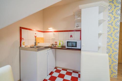a small kitchen with white cabinets and a microwave at Jade Panzio in Balatonföldvár