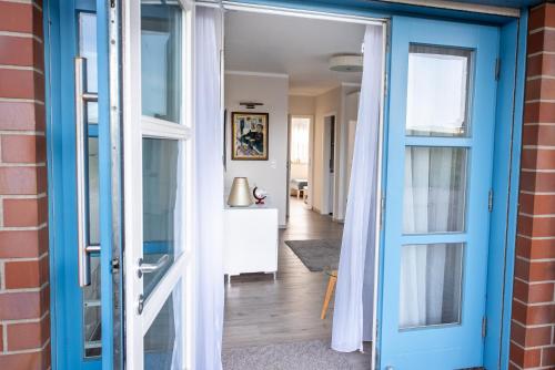 a room with a blue door and a hallway at Moderne Wohnung mit großer Terrasse in erster Reihe am Deich, Wallbox, Kajak in Schönberger Strand